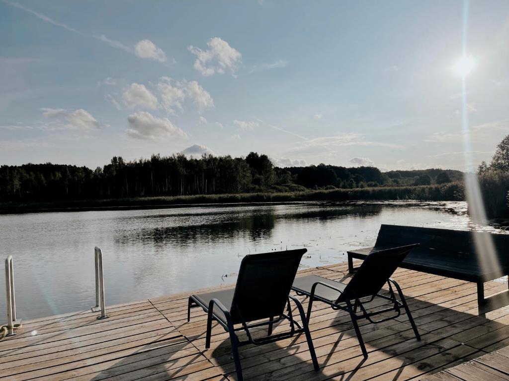 2 Stühle und ein Tisch auf einem Steg neben einem See in der Unterkunft HYGGE Sauna&Fishing House 