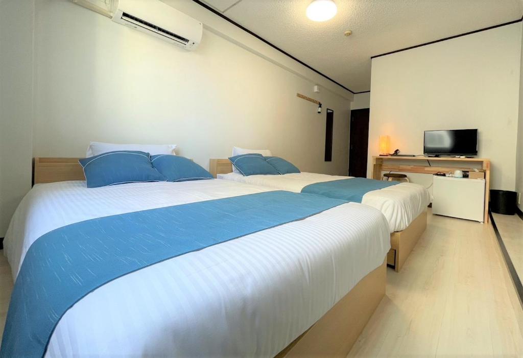 a bedroom with two beds and a flat screen tv at Portside美崎町 離島ターミナル徒歩3分 室内リニューアルOPEN in Ishigaki Island
