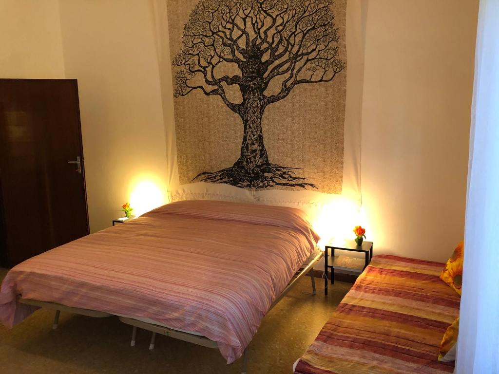 1 dormitorio con 1 cama con una pintura de árbol en la pared en Struttura Alloggio Fabrizio Rimini, en Rímini