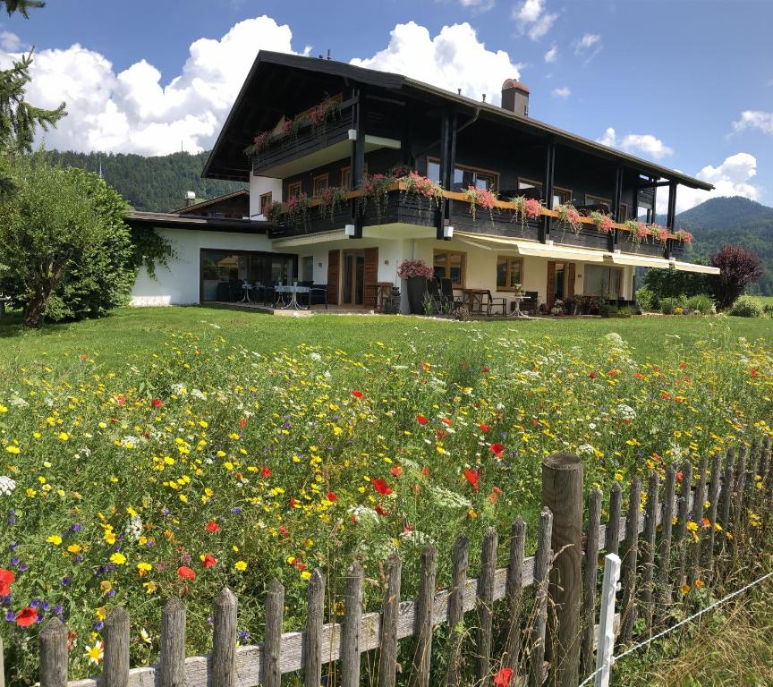 a house behind a fence with a field of flowers at Gästehaus Wiesegg in Reit im Winkl