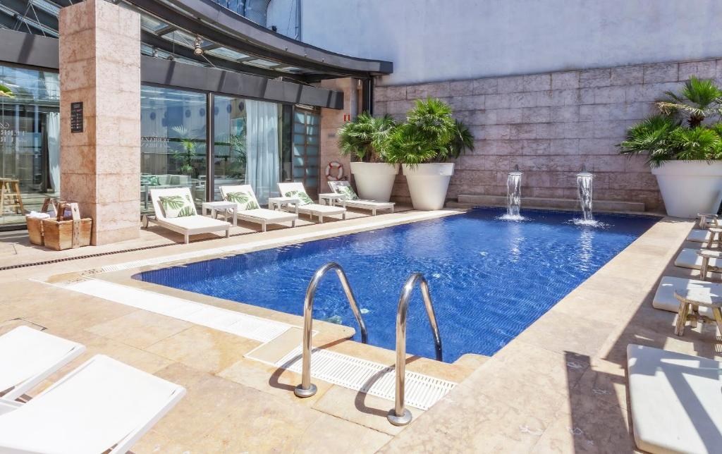 - une piscine avec des chaises longues à côté d'un bâtiment dans l'établissement Hotel Urban,a Member of Design Hotels, à Madrid