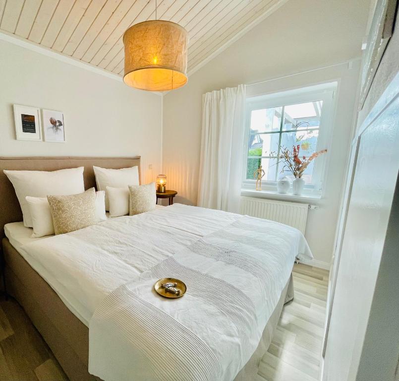 a white bedroom with a large white bed and a window at Strandzone 29 in Kronsgaard