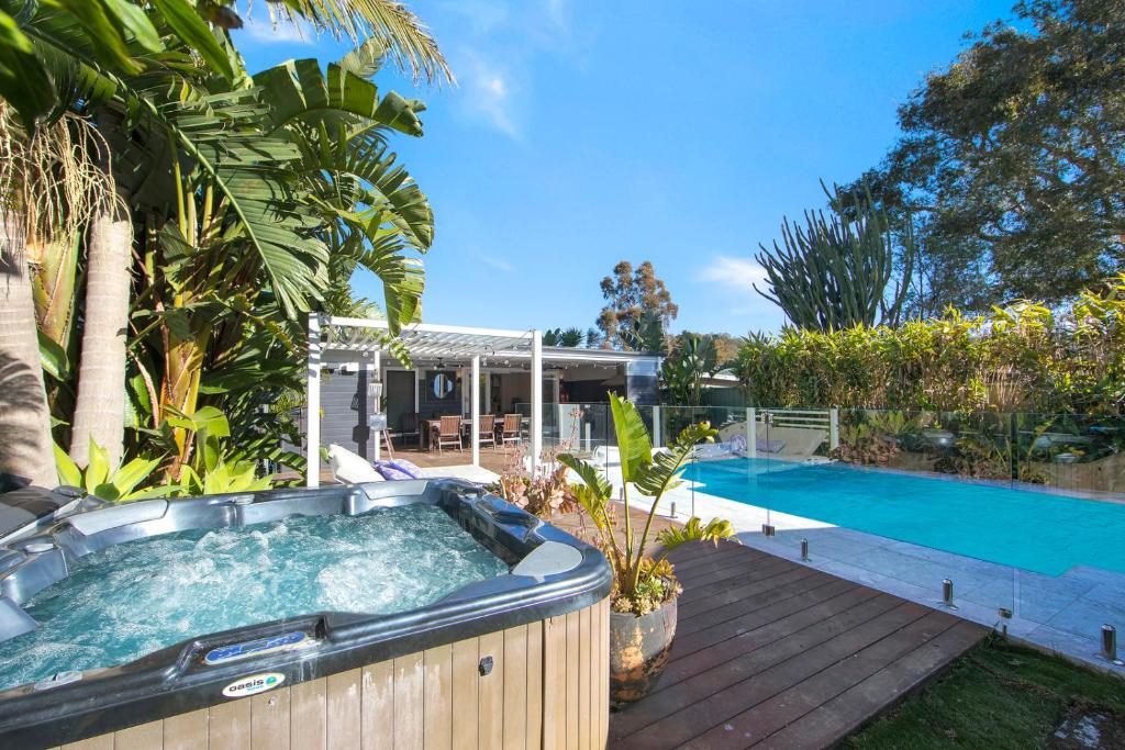 een hot tub in een achtertuin naast een zwembad bij Woy Woy Staycation - Heated Pool & Hot Tub & Games Room in Woy Woy