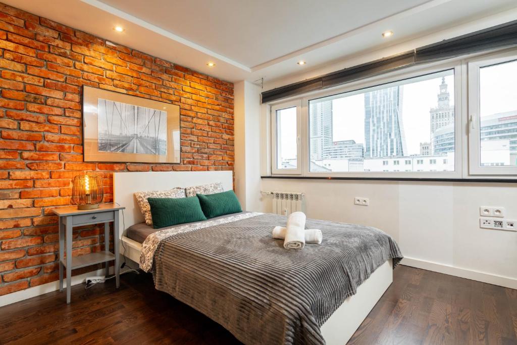 een slaapkamer met een bed en een bakstenen muur bij Chmielna 106B Centrum by VAYA STAYS in Warschau