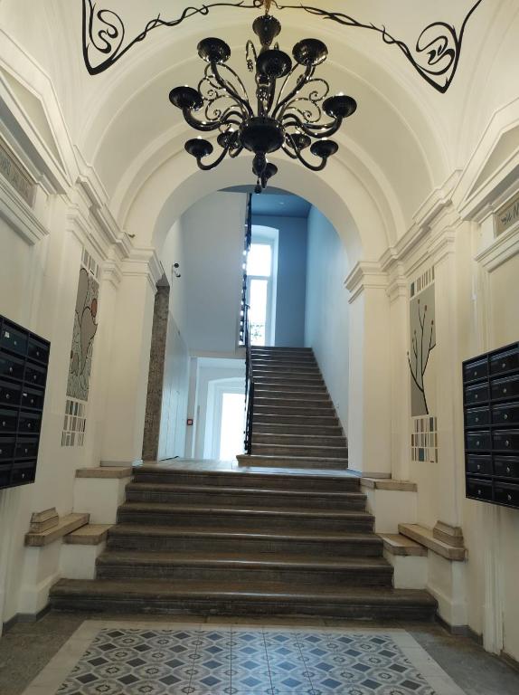 a hallway with a chandelier and stairs in a building at Boutique Apartments Cecilia in Trieste