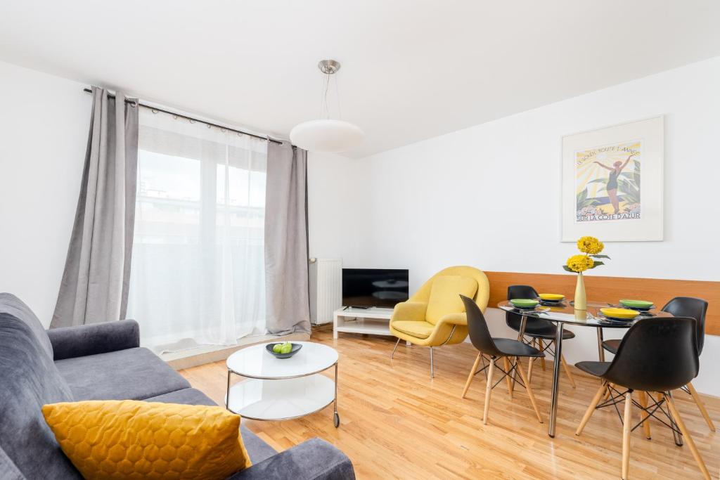 uma sala de estar com um sofá, uma mesa e cadeiras em Modern Apartment with FREE parking spot na Cracóvia