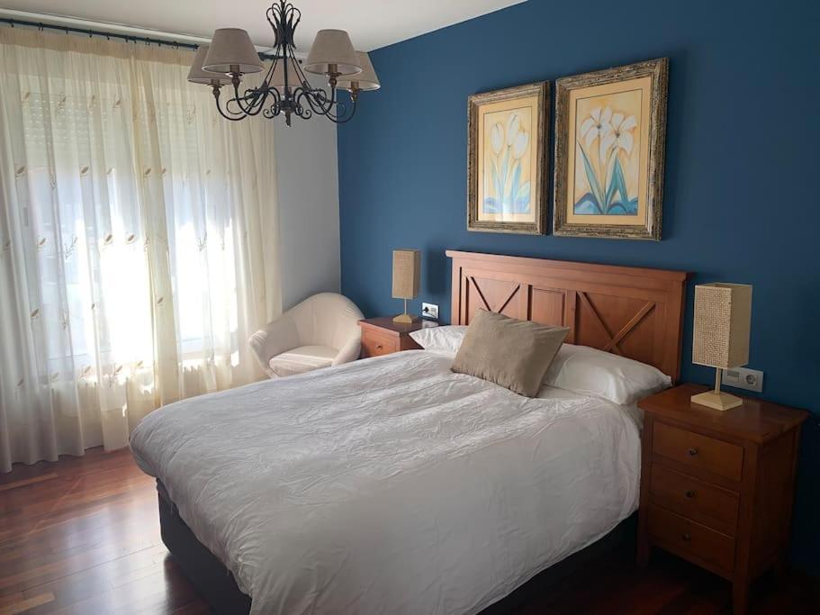 1 dormitorio con cama y pared azul en Piso de la pala, en Pontevedra