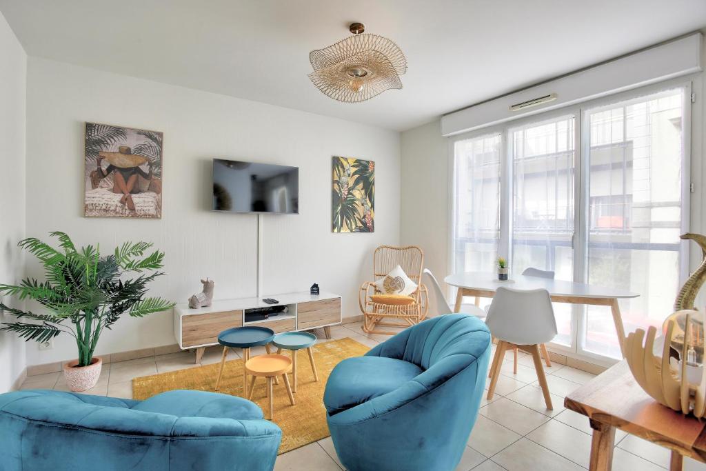 uma sala de estar com cadeiras azuis e uma mesa em Expédition Malouine - Appt à 30m de la plage em Saint Malo