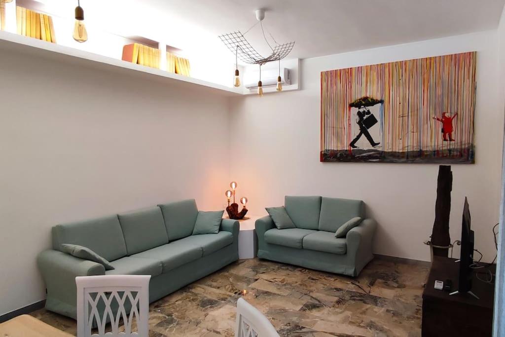 un soggiorno con 2 divani verdi e un dipinto di Sunnyhome- Ostia Lido vista mare 2 bagni a Lido di Ostia