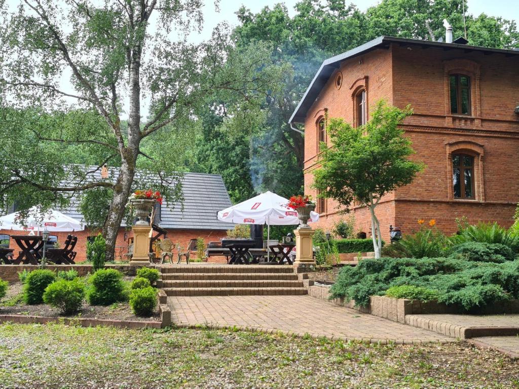 un edificio de ladrillo con una mesa y una sombrilla delante de él en Dwór Mysinek, en Grabowiec