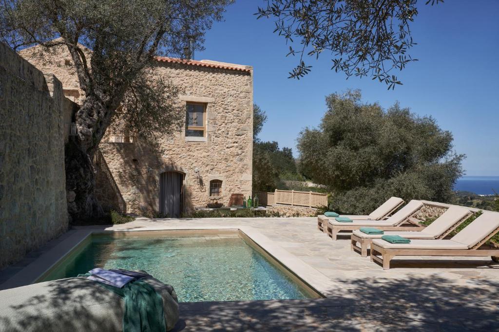 una piscina con sedie a sdraio accanto a un edificio di Kapsaliana Village Hotel a Kapsalianá