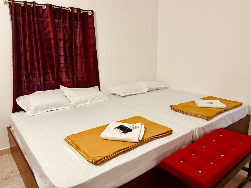 a white bed with two towels and a red chair at DE Villa Breeze @ Beach side in Pondicherry