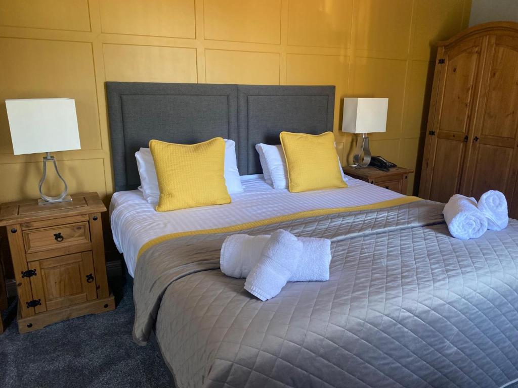 a bedroom with a large bed with towels on it at The Oaks Hotel in Alnwick