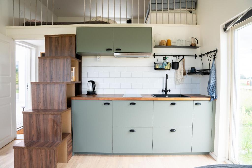 una cocina con armarios blancos y fregadero en Your own 30sqm house with kitchen, sauna and loft. en Malmö