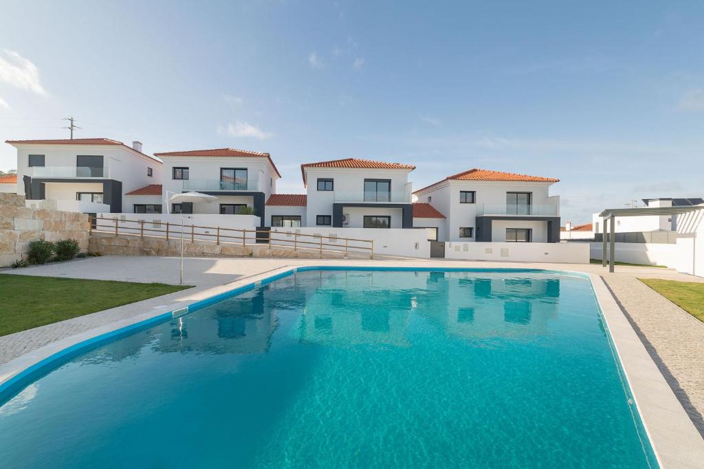 uma grande piscina azul em frente a algumas casas em Palhanas - Holiday Homes - By SCH em Salir de Porto