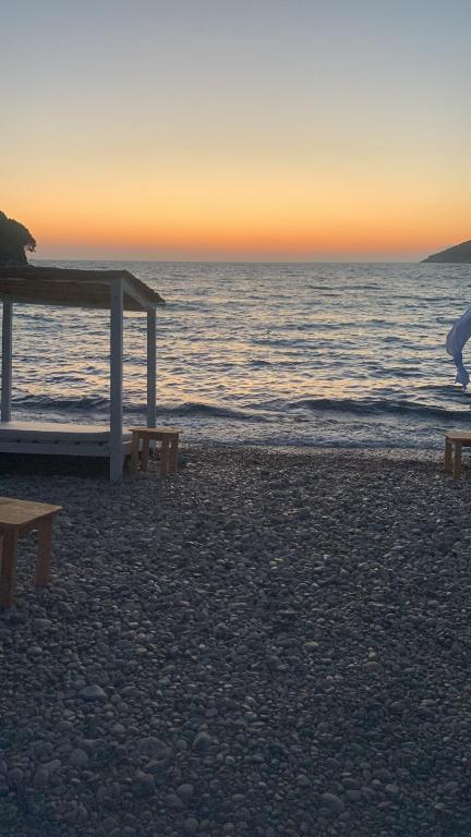 a beach with benches and the ocean at sunset at ZLATNI LEPTIR in Dobra Voda