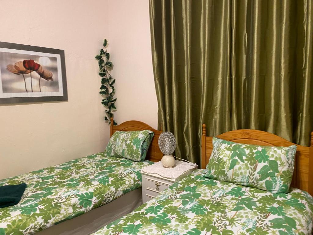 two beds in a room with green curtains at CHARLES INN in Liverpool