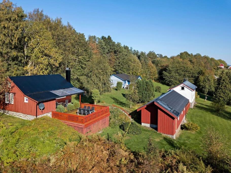 a red barn with a black roof on a hill at Feriehus nær badeplass og Molde sentrum in Årø