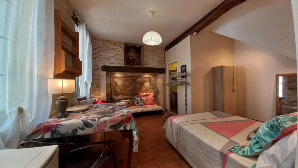 een slaapkamer met 2 bedden en een open haard bij Oh P'tit Rapporteur in Montcuq