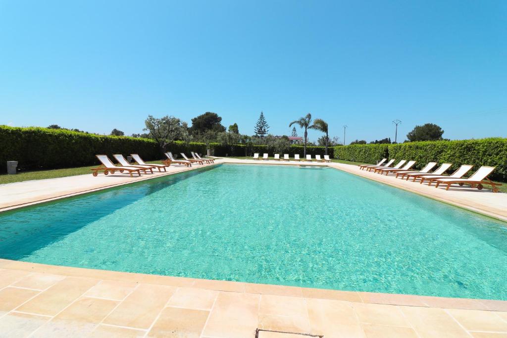 uma grande piscina com espreguiçadeiras num resort em Torre Santo Stefano em Otranto