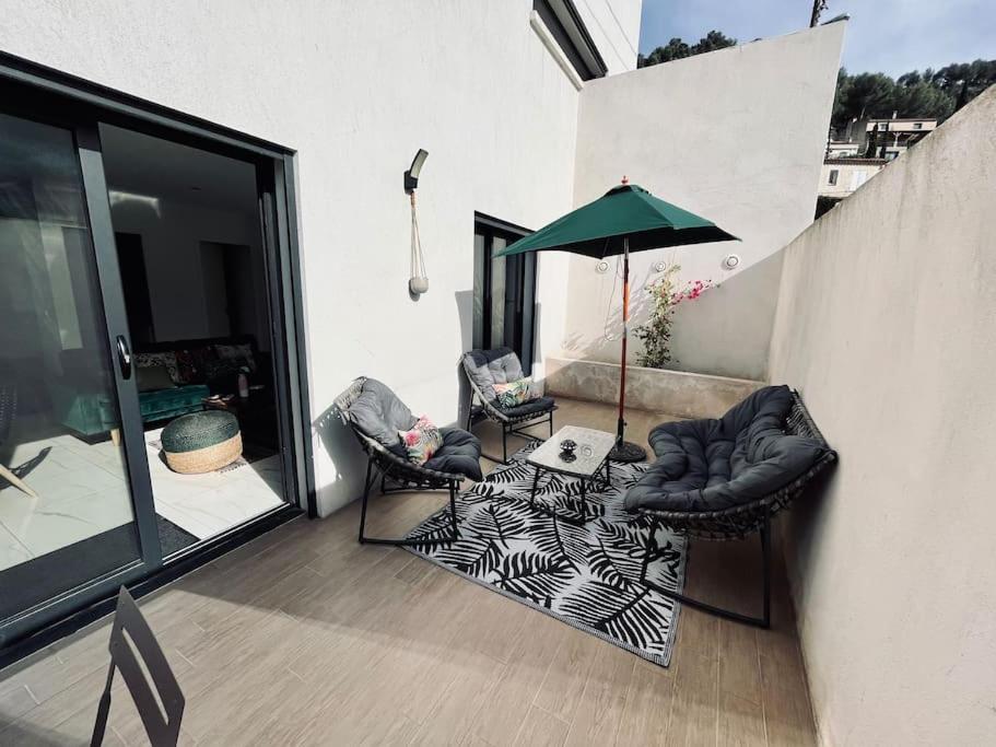 a patio with two chairs and a table with an umbrella at Le Berceau Vert in Marseille