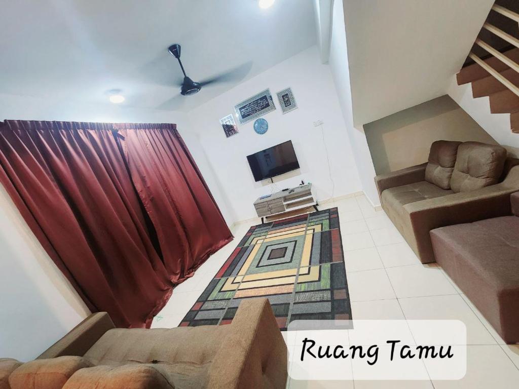 uma sala de estar com um sofá e uma televisão em Ro-z Homestay em Rantau Panjang
