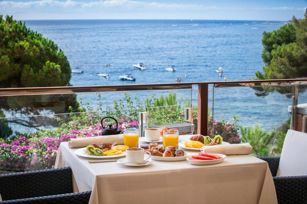 una mesa con comida y vistas al océano en Hotel Cala del Pi - Adults Only, en Platja d'Aro