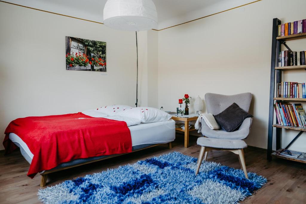 1 dormitorio con 1 cama, 1 silla y 1 alfombra azul en Ferienwohnung Morgensonne, en Schützen am Gebirge