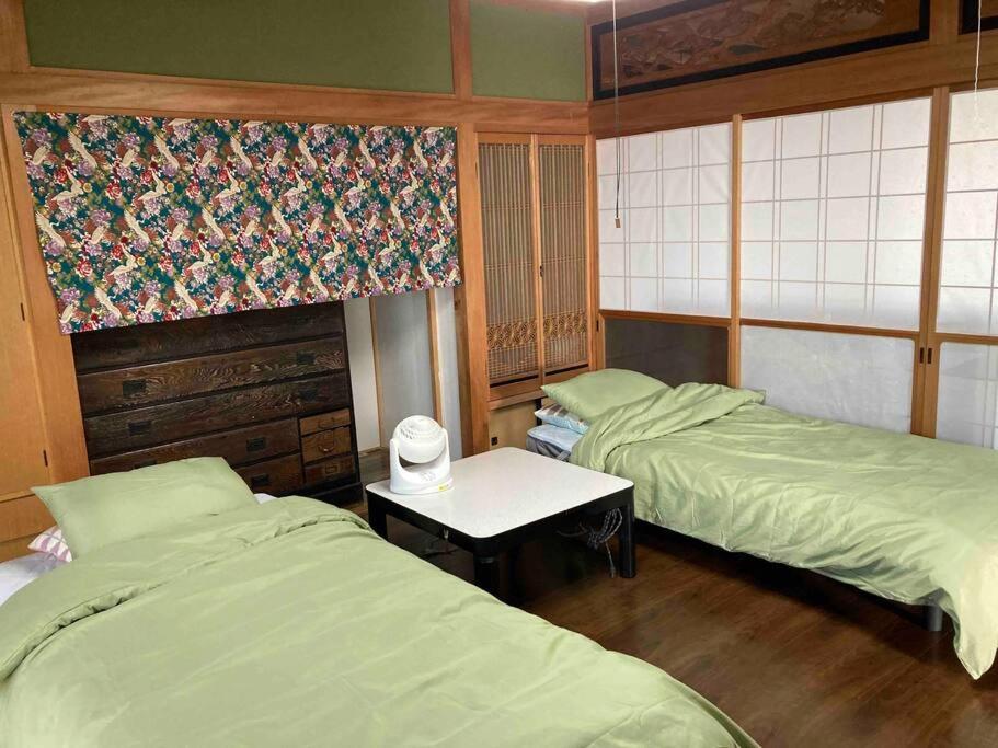 Habitación con 2 camas y mesa. en 桂浜龍馬に1番近い宿ペットと泊れる一軒家龍馬庵, en Kochi