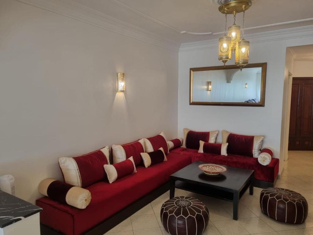 uma sala de estar com um sofá vermelho e uma mesa em Appartement spacieux et agréable em Tânger