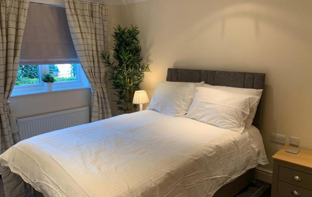um quarto com uma cama grande com lençóis brancos e uma janela em Addlestone - Stylish and modern 2 bedroom apartment em Addlestone