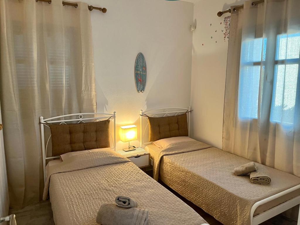 two beds in a small room with a window at My Naxian Home 1 in Agios Prokopios