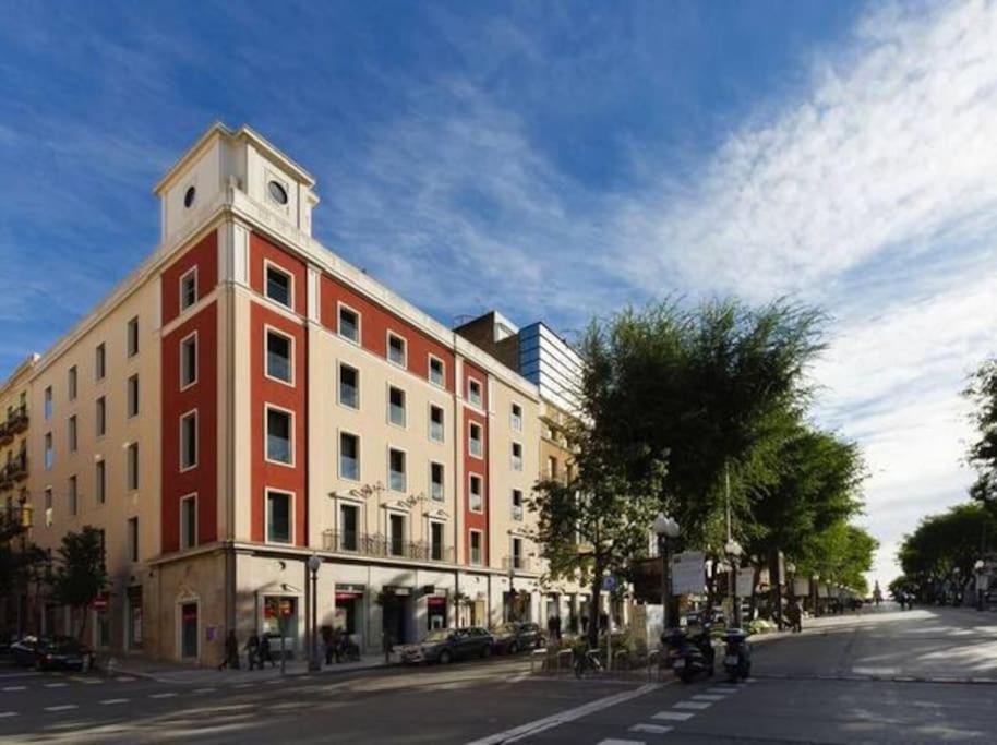 un grande edificio rosso con una torre dell'orologio su una strada di Stunning & Modern Penthouse - Rambla - City centre a Tarragona
