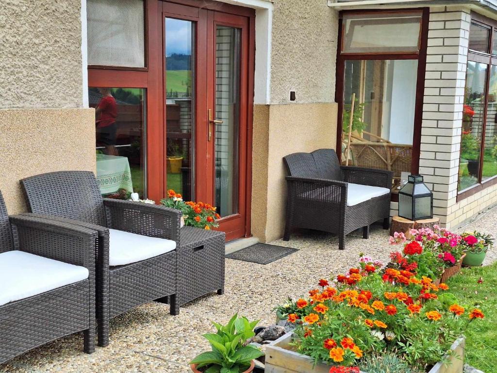 eine Terrasse mit Korbstühlen und Blumen im Garten in der Unterkunft Apartmán pod Maliarkou in Východná