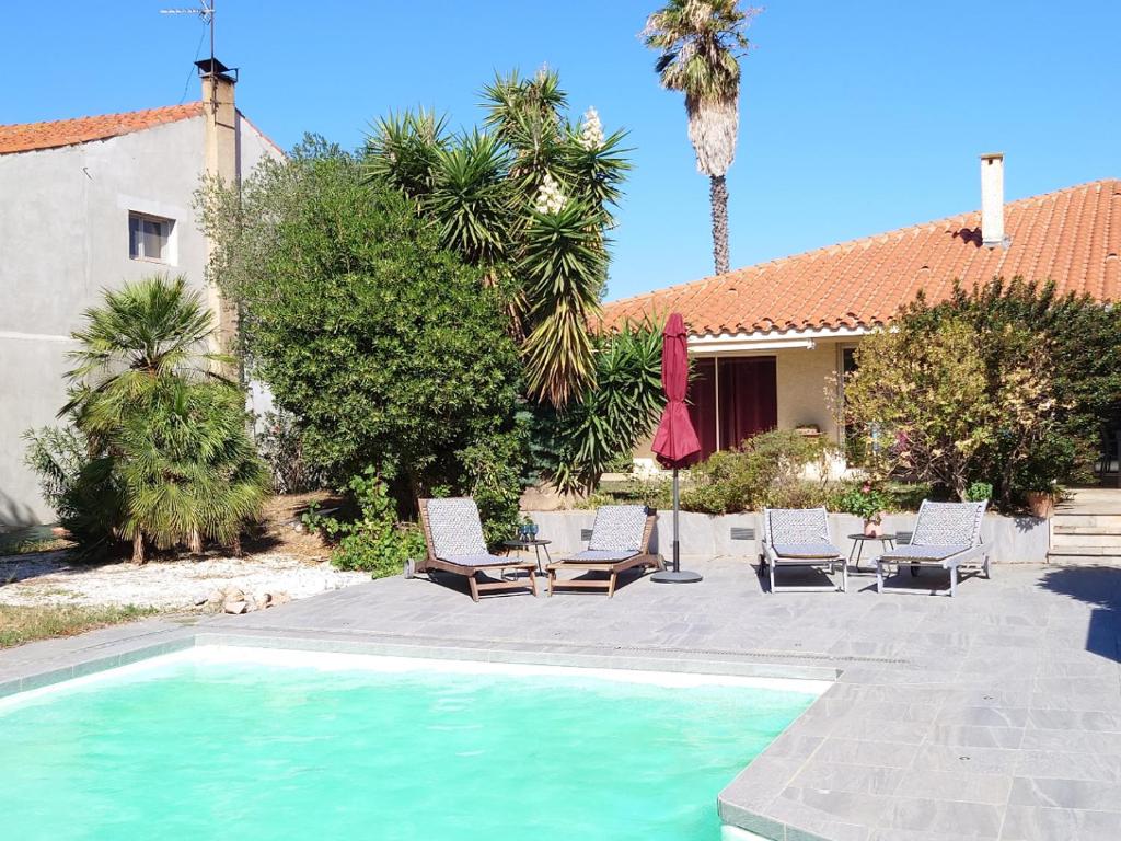 a villa with a swimming pool and chairs and a house at TOUTUNCINEMER in Saleilles