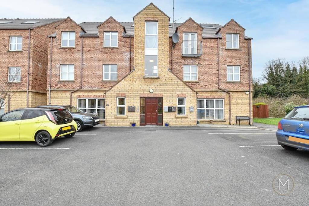 a parking lot in front of a large brick building at Modern Apartment by river - 20 mins to Belfast in Dunadry