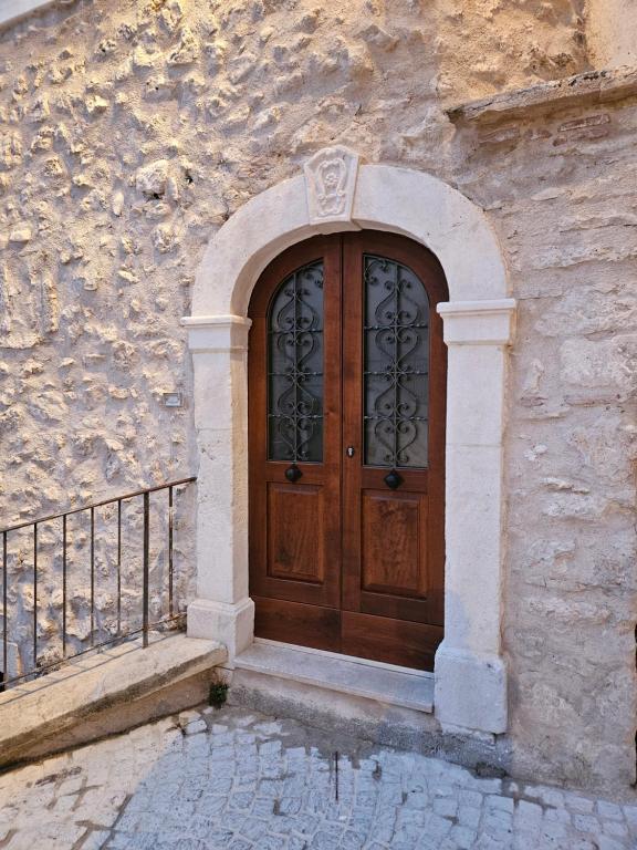 une porte en bois sur un bâtiment avec un mur en pierre dans l'établissement DESTASU' Apartments, à Castel del Monte