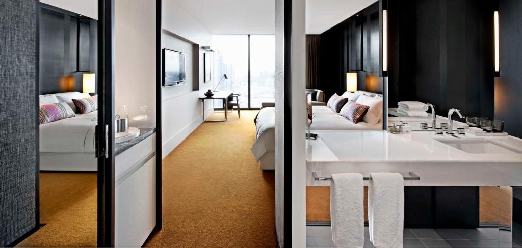uma casa de banho com 2 camas, um lavatório e um espelho. em Crown Metropol Melbourne em Melbourne