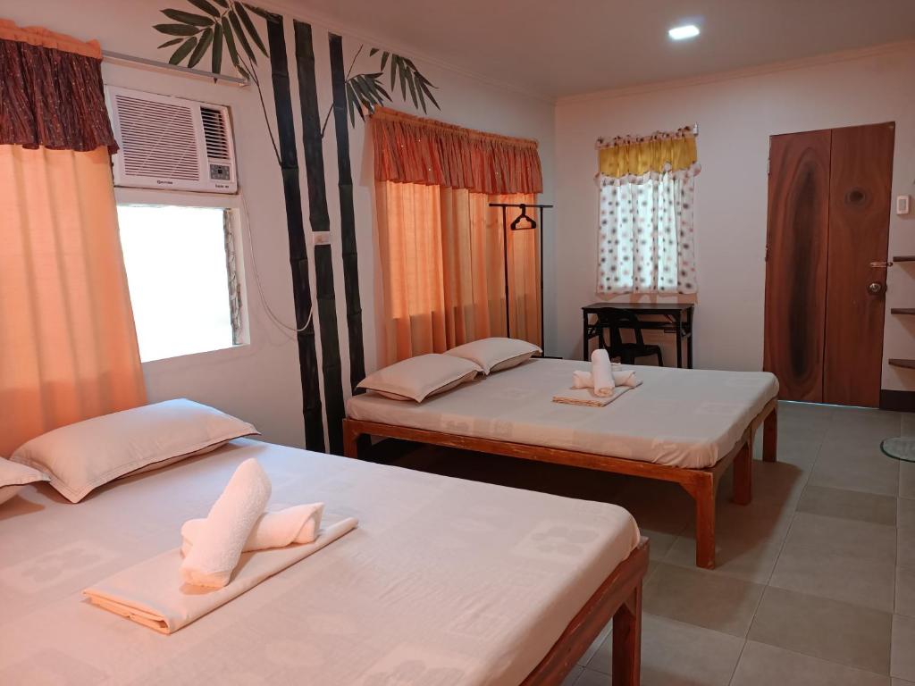 two beds in a room with orange curtains at Agta Beach Resort in Biliran