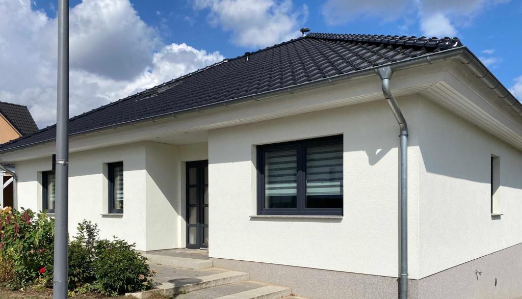 une maison blanche avec un toit noir dans l'établissement Ferienwohnung Sea-Bike-Soul, à Neubrandenbourg