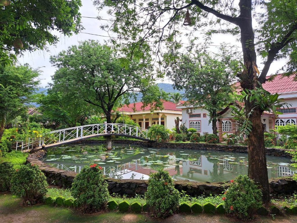 eine Brücke über einen Teich vor einem Gebäude in der Unterkunft Xuanmai Garden Resort in Pakse