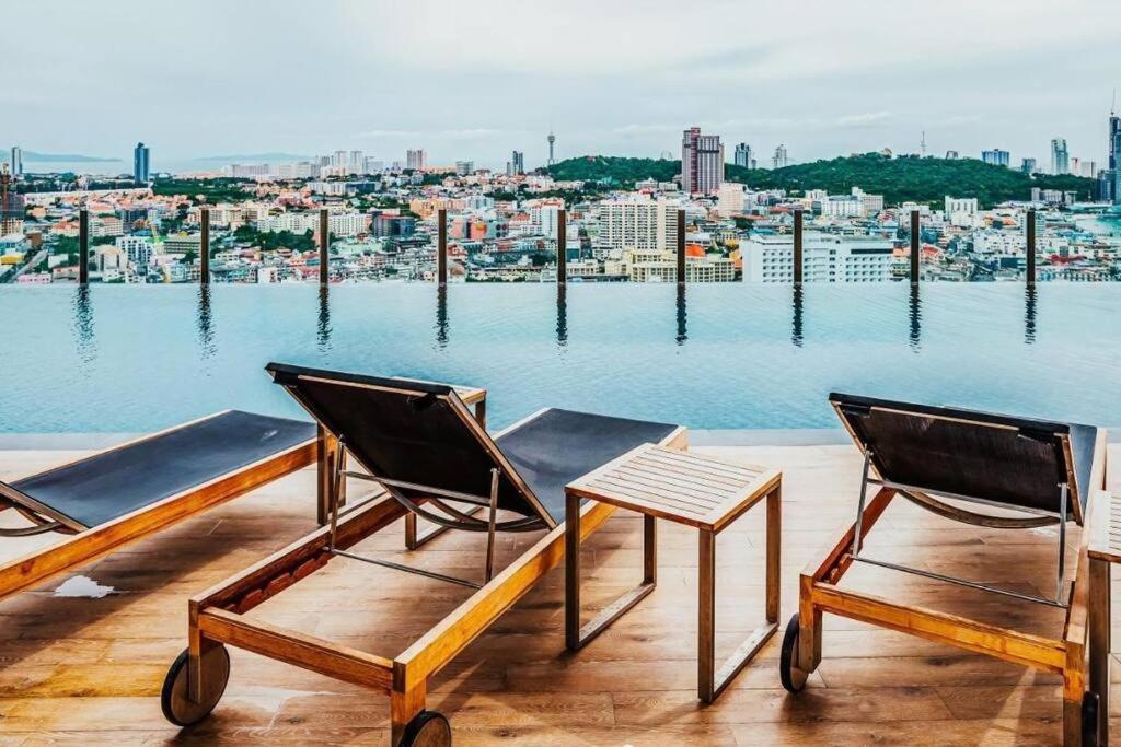 two chairs and a table on a balcony overlooking the water at Pattaya Central & Infinity Pool in Pattaya Central