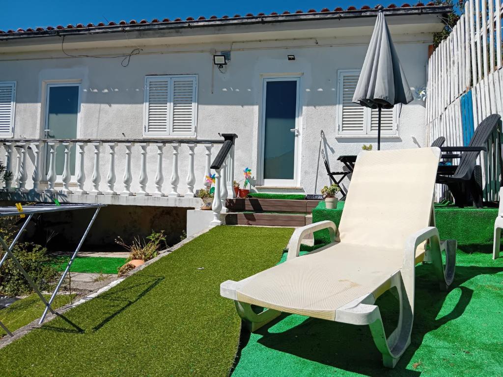 a white chair and an umbrella on a yard at Quiet 1 bed house with kitchen Viana do Castelo in Viana do Castelo