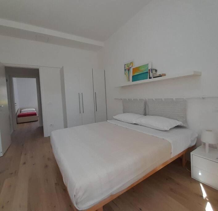 una camera bianca con un grande letto e un pavimento in legno di Casacciuga, luminosa e centrale casa con giardino a Pesaro
