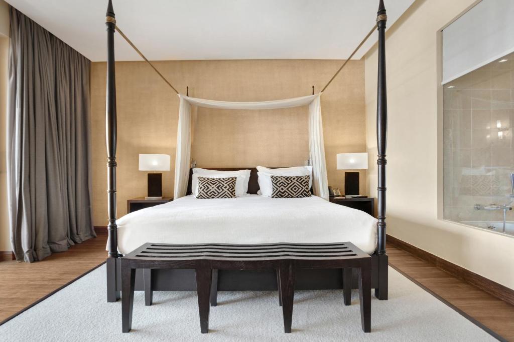 a bedroom with a four poster bed with white sheets at Cascade Wellness Resort in Lagos