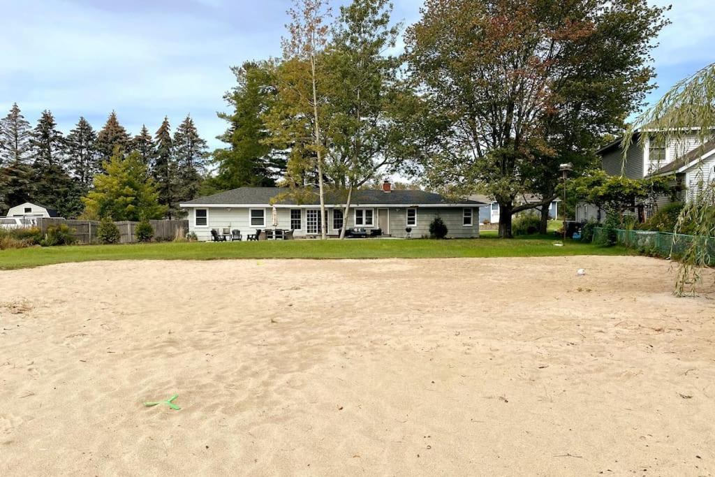 a house sitting on the beach with a sandy field at HOT TUB - Grand Haven/Spring Lake Waterfront Home in Spring Lake