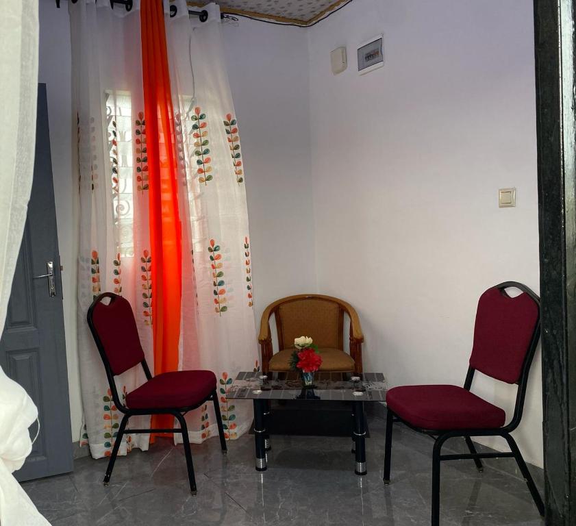 twee rode stoelen en een tafel in een kamer bij Studio meublé in Douala