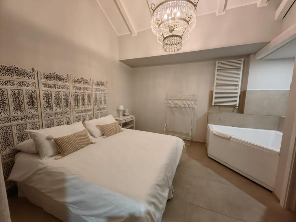コルマーノにあるB&B De I Braviのベッドルーム1室(ベッド1台、バスタブ、シャンデリア付)