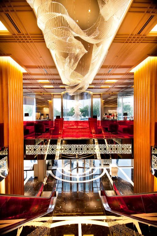 a restaurant with red chairs and a large ceiling at The Marmara Taksim in Istanbul