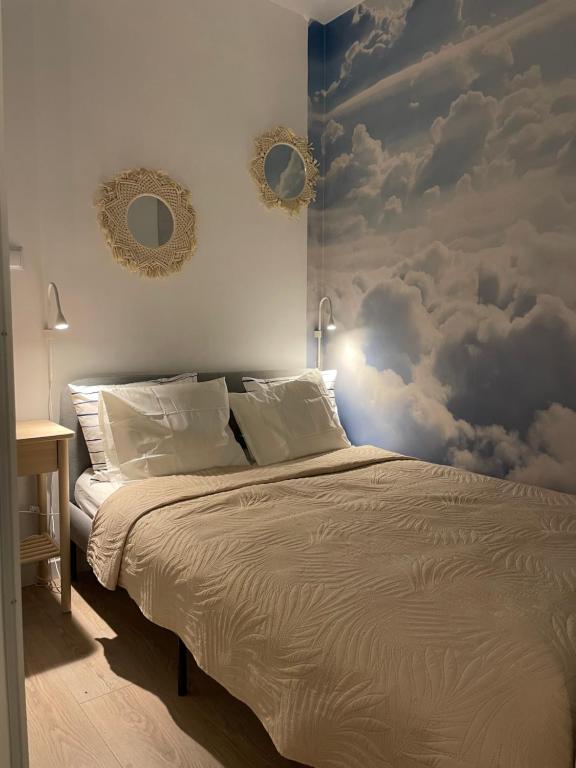 a bedroom with a bed with clouds on the wall at LeHome Airport Wroclaw in Wrocław